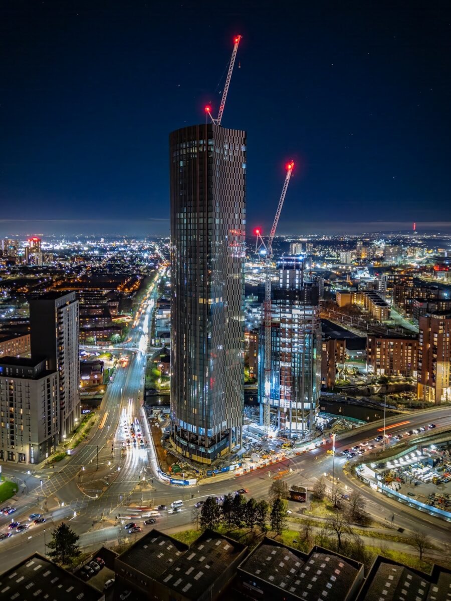 Skyscrapers under construction at night with city lights.